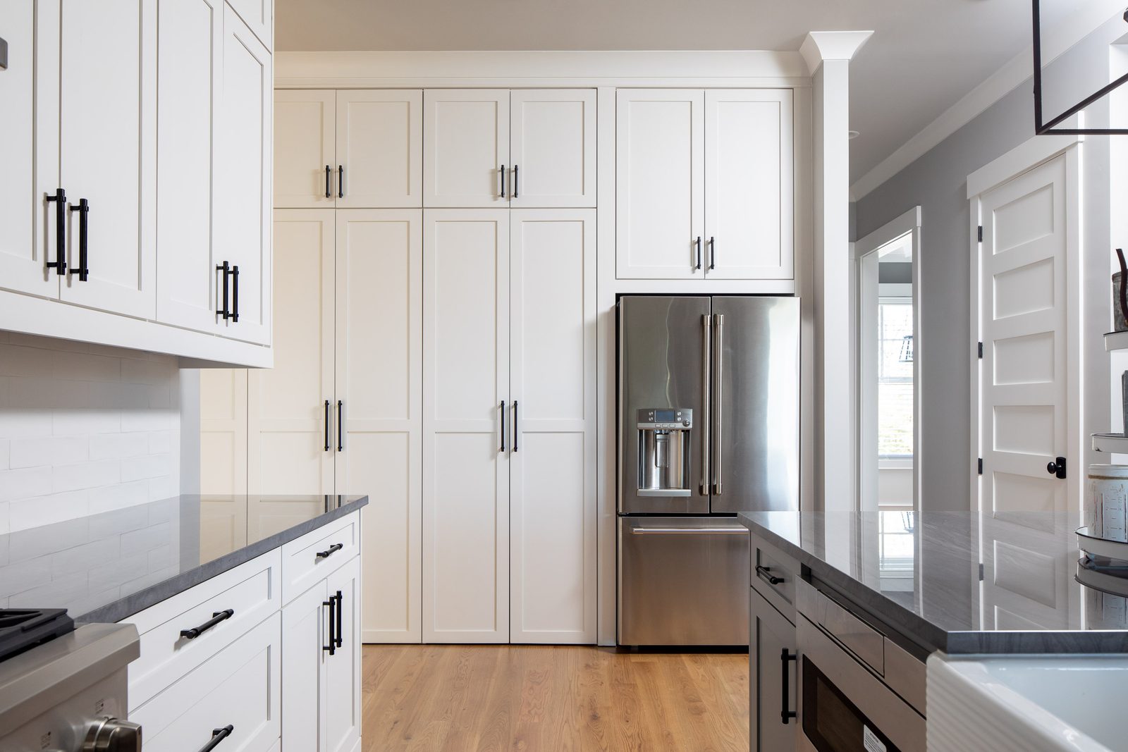 Kitchen cabinetry with counter-depth refrigerator and dark counters — Glausier, custom home built by Ironwood Construction Group