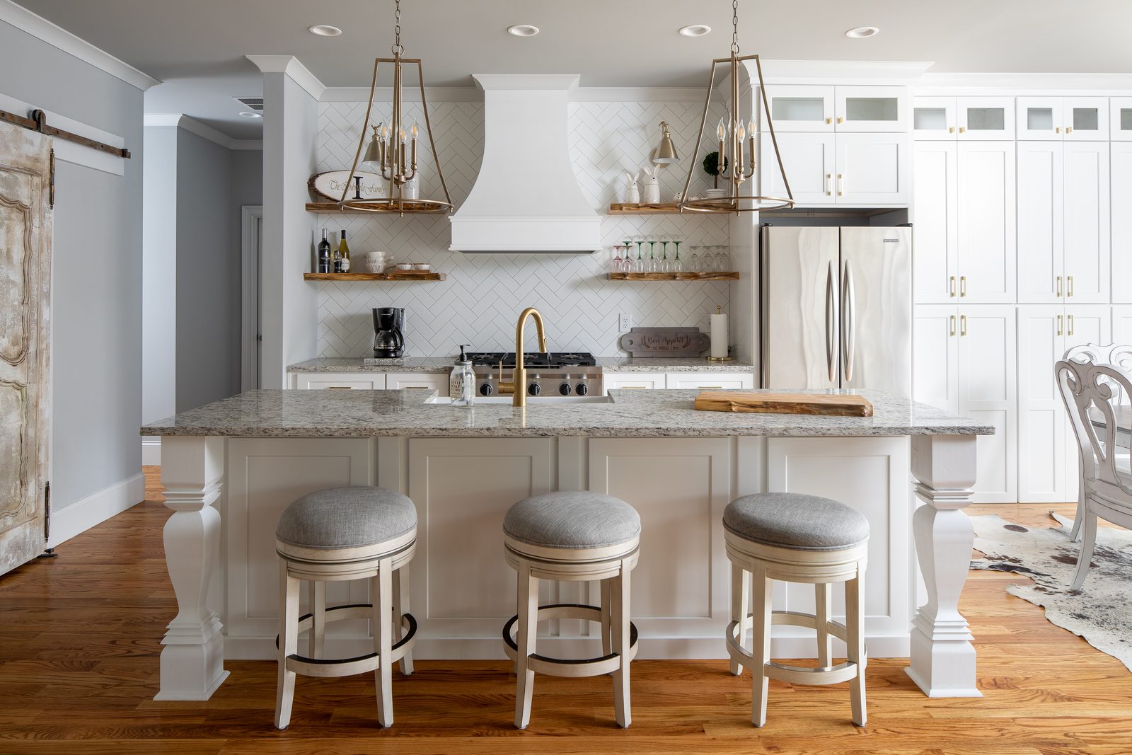 Kitchen with granite island, white cabinets and floating shelves — Spring 2020 Custom Home, custom home built by Ironwood Construction Group
